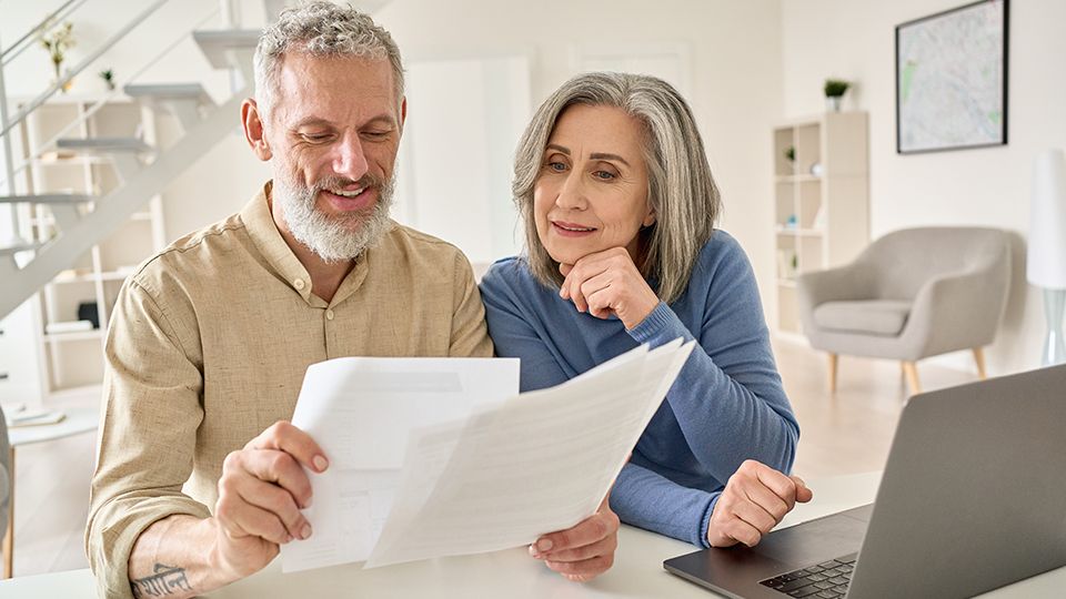 Elderly couple looking at papers inside their home