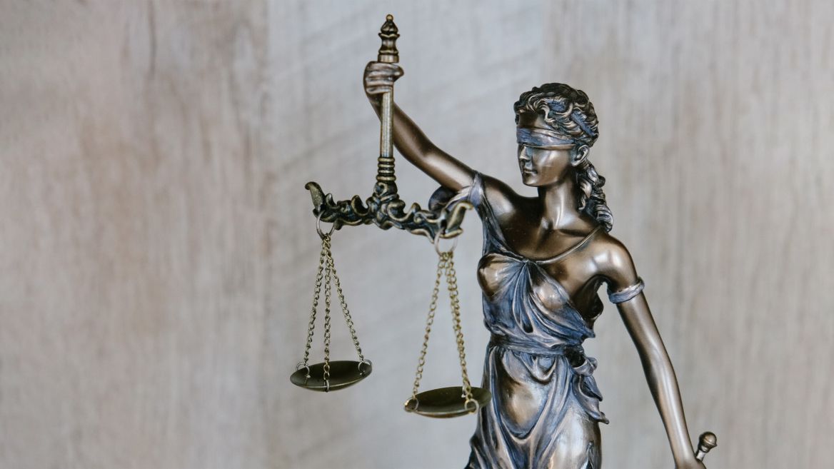 A statue of a blindfolded woman holds the scales of justice